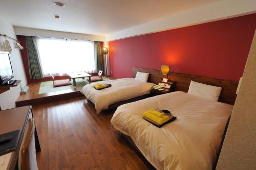 a hotel room with two beds and a red wall at Yakushima Green Hotel in Yakushima