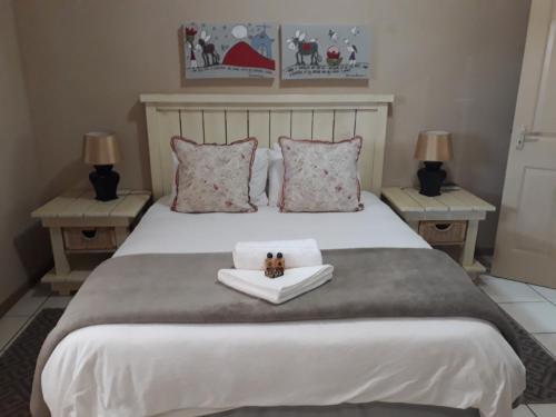 a bedroom with a large white bed with two tables at Augrabies De Oude Stoor Guesthouse in Augrabies