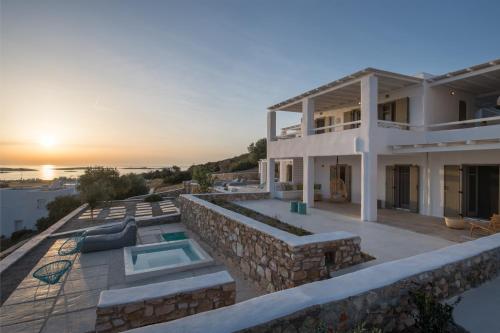 a villa with a swimming pool and a sunset at Ciel Villas Paros in Pounda