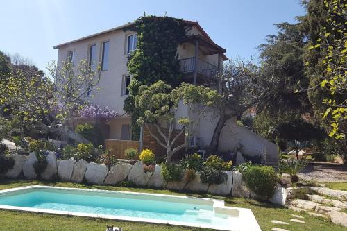 une maison avec une piscine en face d'une cour dans l'établissement Villa LES FIGUIERS, à Cavalaire-sur-Mer