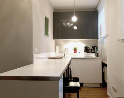 una cocina con encimeras blancas y armarios negros en Berlin Style Apartments - Schönholzer Straße, en Berlín