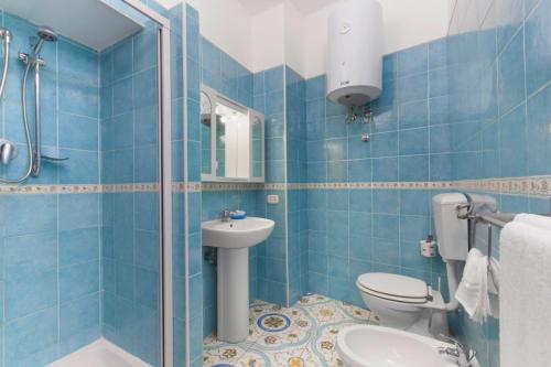 a blue tiled bathroom with a toilet and a sink at Sorrento Marida Rooms in Sorrento