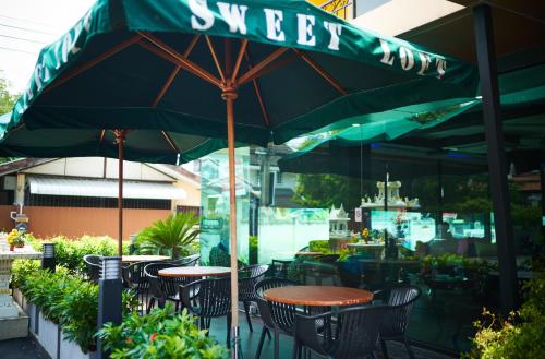 a patio with tables and chairs under an umbrella at Sweetloft Hotel Don Muang in Bangkok