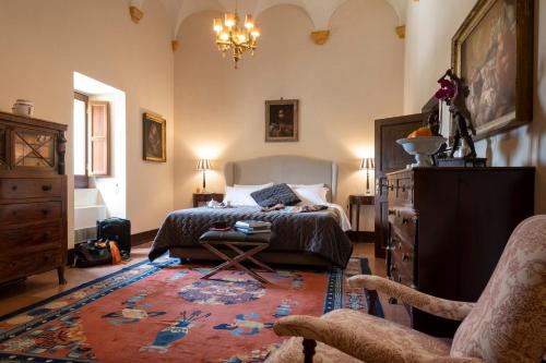 a bedroom with a bed and a chair and a rug at Abbazia Santa Maria del Bosco in Contessa Entellina