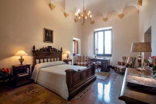 Abbazia Santa Maria del Bosco في Contessa Entellina: غرفة نوم بسرير وطاولة وكراسي
