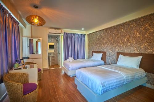 a hotel room with two beds and a chair at Sweetloft Hotel Don Muang in Bangkok