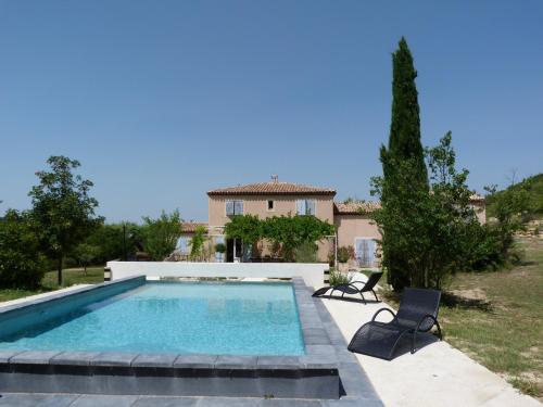 a swimming pool with two chairs and a house at Le Mas de Pié Caud in Rognes