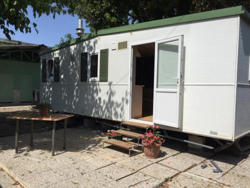 a white and green trailer with a table and flowers at Camping Verde in Massa