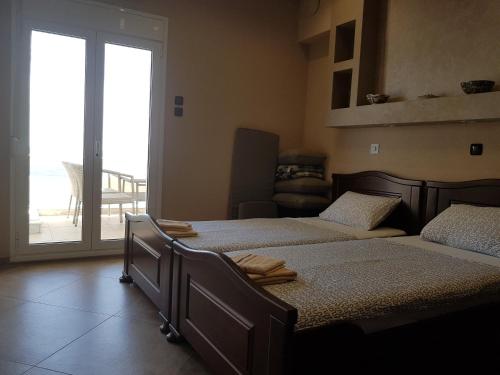 a bedroom with two beds and a sliding glass door at Luxury apartment on the first line ! in Nea Kalikratia
