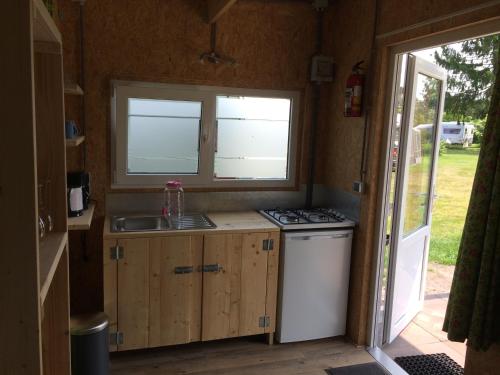 una cucina con lavandino, piano cottura e finestra di Trekkershut a Beilen