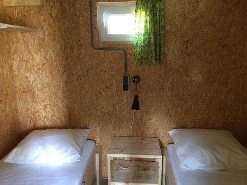 1 dormitorio con 2 camas, ventana y mesa en Trekkershut, en Beilen