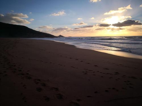 a sunset on a beach with footprints in the sand at Appartamento Belvedere Sassos P 3267 in Tresnuraghes