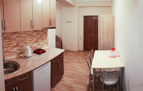 a kitchen with a sink and a table with chairs at Hotel Tao in Batumi