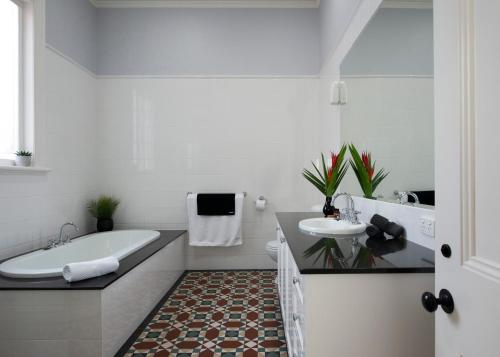 a white bathroom with a tub and a sink at House at No. 10 in Ballarat