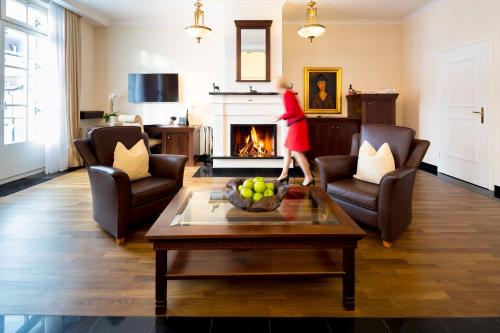 a woman walking through a living room with a fireplace at Grand Hotel des Bains Kempinski in St. Moritz
