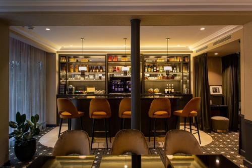 a bar in a hotel room with stools at Lenox Montparnasse in Paris