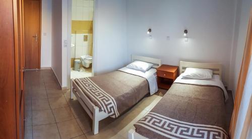 a hotel room with two beds and a bathroom at Zouboulia Apartments in Kardamaina