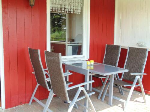 a table and chairs in front of a red wall at Idyllic Bungalow in Damshagen near Baltic Sea in Reppenhagen