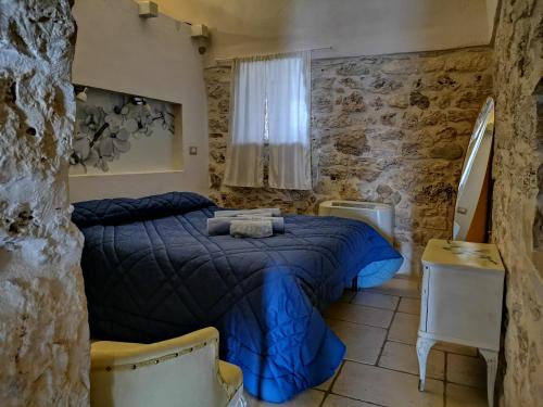 sypialnia z niebieskim łóżkiem i kamienną ścianą w obiekcie Trullo Madia e Dimora Giorgio w mieście Ceglie Messapica