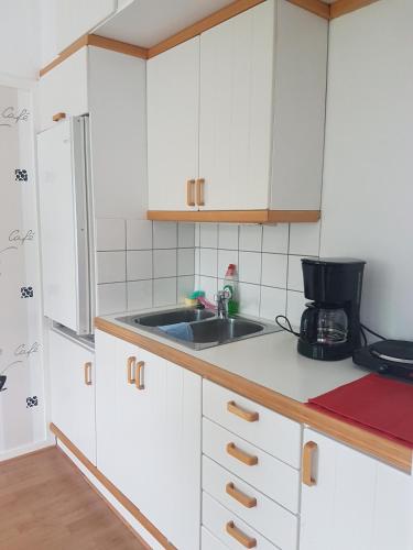 een keuken met witte kasten en een wastafel bij Gamla Macken in Margretetorp