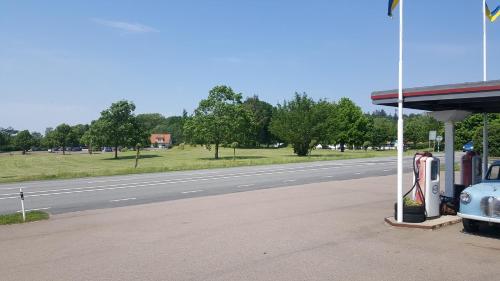 um posto de gasolina com um carro estacionado ao lado de uma estrada em Gamla Macken em Margretetorp