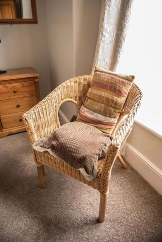 a wicker chair with a pillow in a room at Glendower in St. Davids