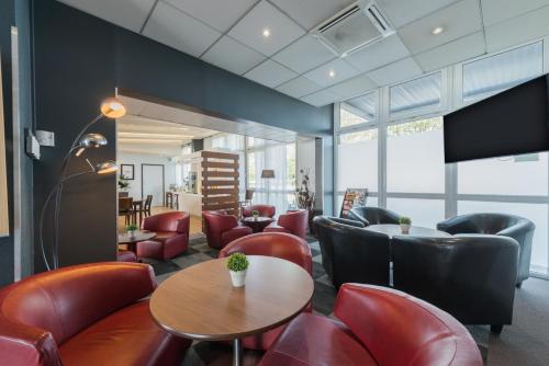 a waiting room with red leather chairs and tables at Kyriad Marne-La-Vallée Torcy in Torcy