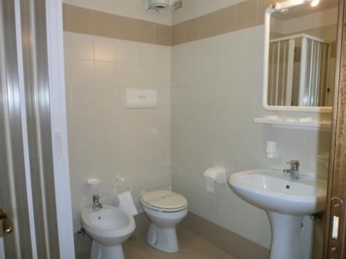 a white bathroom with a toilet and a sink at Casa Montana S. Maddalena in San Vito di Cadore