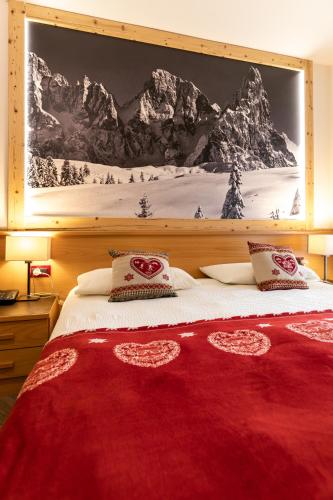 a bedroom with a red bed with a mountain mural at Hotel Isolabella Wellness in Fiera di Primiero
