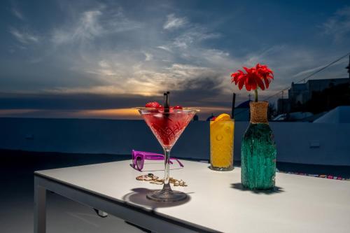 a table with a drink in a martini glass and two vases at Labyrinth Traditional Houses in Pirgos