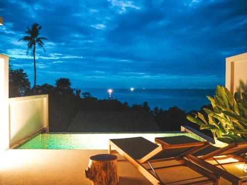 a patio with a view of the ocean at night at Mayara pool villas in Haad Yao