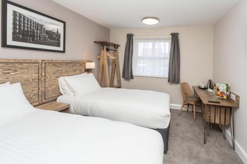 a hotel room with two beds and a desk at The Aviator, formerly Smugglers Cove, Clacton On Sea by Marston's Inns in Clacton-on-Sea