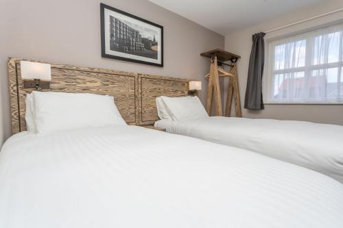 two white beds in a bedroom with a window at The Aviator, formerly Smugglers Cove, Clacton On Sea by Marston's Inns in Clacton-on-Sea