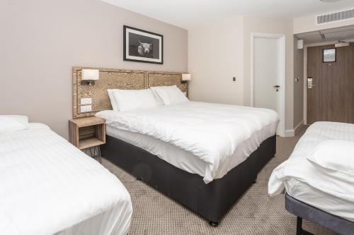 a hotel room with two beds with white sheets at The Aviator, formerly Smugglers Cove, Clacton On Sea by Marston's Inns in Clacton-on-Sea