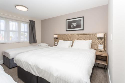 two beds in a room with white walls and windows at The Aviator, formerly Smugglers Cove, Clacton On Sea by Marston's Inns in Clacton-on-Sea