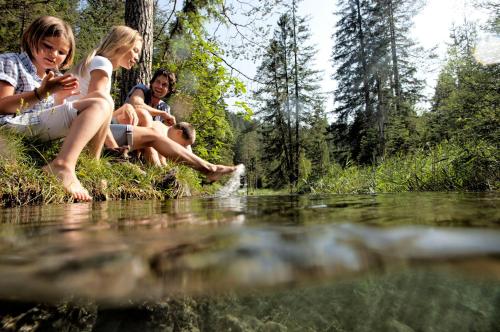 a group of people sitting on the shore of a river at B&B Gästehaus Alpenblick in Lermoos