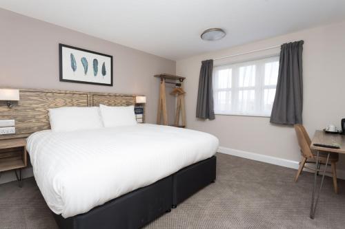 a bedroom with a bed and a desk and a window at The Aviator, formerly Smugglers Cove, Clacton On Sea by Marston's Inns in Clacton-on-Sea