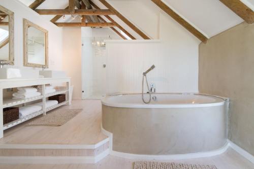 a large bathroom with a tub and a sink at Fin Whale Beach House in Kommetjie