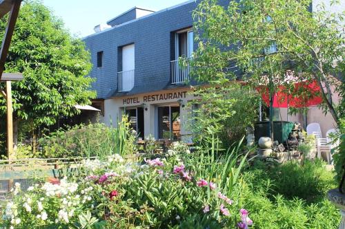 una casa con un jardín con flores delante en Les Bruyeres, en Plélan-le-Grand