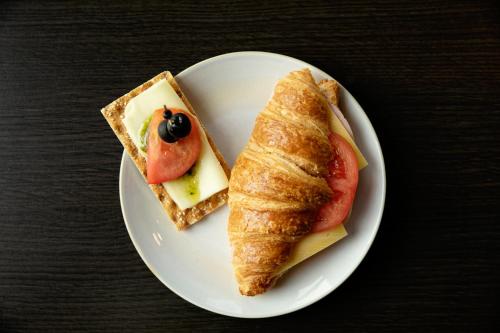 a white plate with a piece of bread and a sandwich at Quentin Prague Hotel in Prague