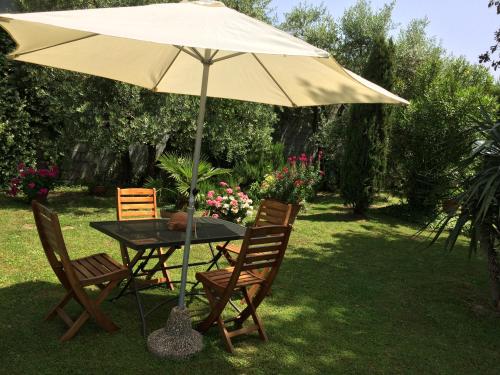 a table and chairs under an umbrella in the grass at La casa dei nonni in Larciano