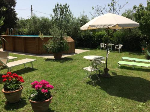 a yard with a table and an umbrella and flowers at La casa dei nonni in Larciano