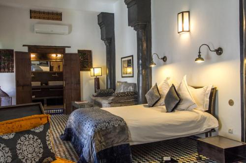 a bedroom with a bed and a living room at Riad Laaroussa in Fez