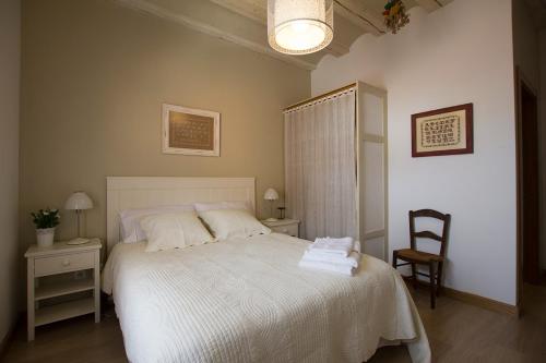 a bedroom with a white bed and a chair at Casa Rural Villazón II - A 16 km de Pamplona in Obanos