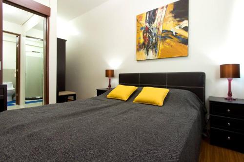 1 dormitorio con 1 cama con 2 almohadas amarillas en The Beacon Makati for 4 WIFI 16mbps, en Manila