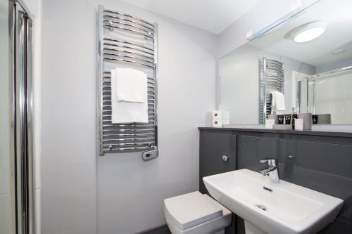 a bathroom with a sink and a toilet and a mirror at Bank Square Town House in Belfast
