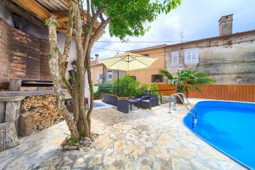 a pool in a yard with a tree and a house at Holiday Home Traum in Krk