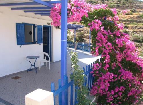 a blue fence with pink flowers in front of a house at Villa Costa Studios in Vathi, Sifnos