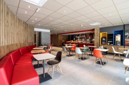 a restaurant with a red couch and tables and chairs at ibis Cahors in Cahors