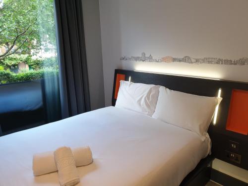 a bedroom with a bed with white sheets and a window at easyHotel London City Shoreditch in London
